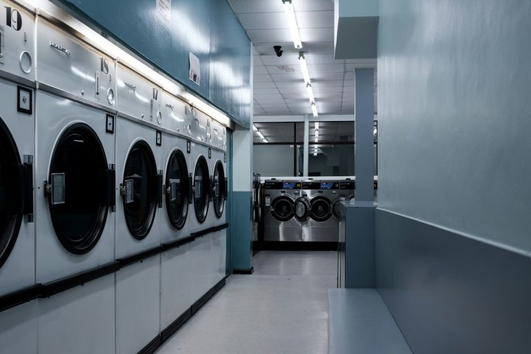 Interior outlet laundry koin dengan deretan mesin cuci dan pengering
