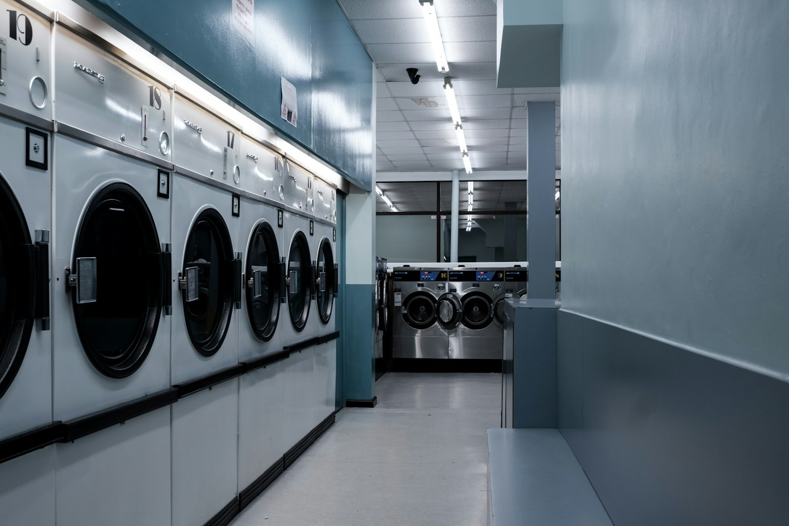 Interior outlet laundry koin dengan deretan mesin cuci dan pengering